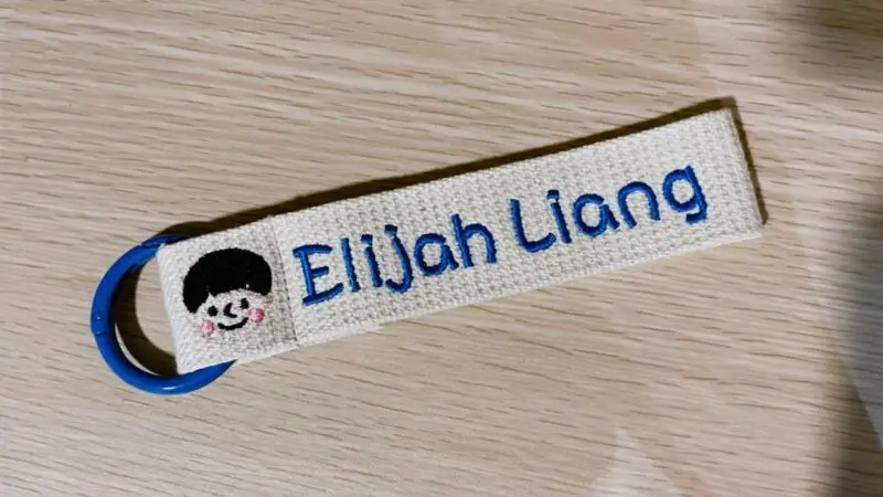 customised bag tag with colour and boy face with name on table